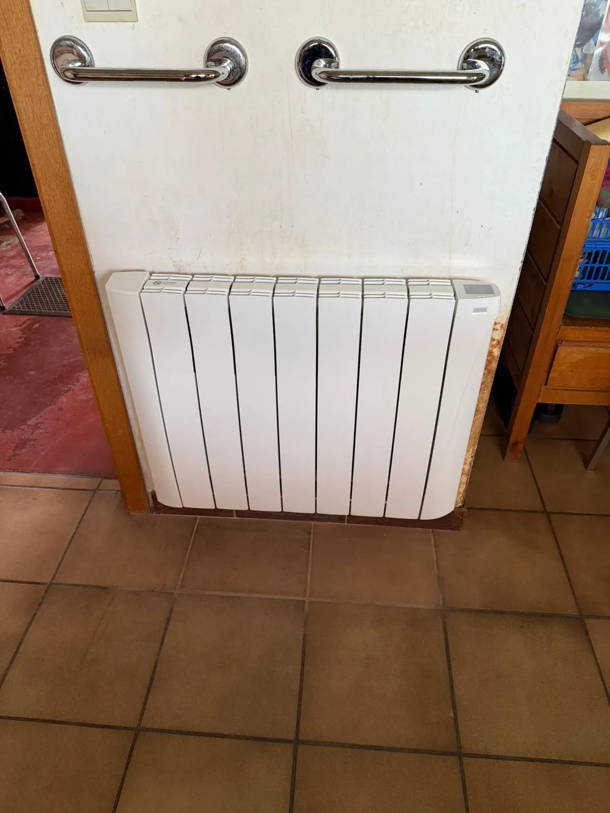 Radiateur Eco Chaleur installé dans une entrée sous un porte-serviettes