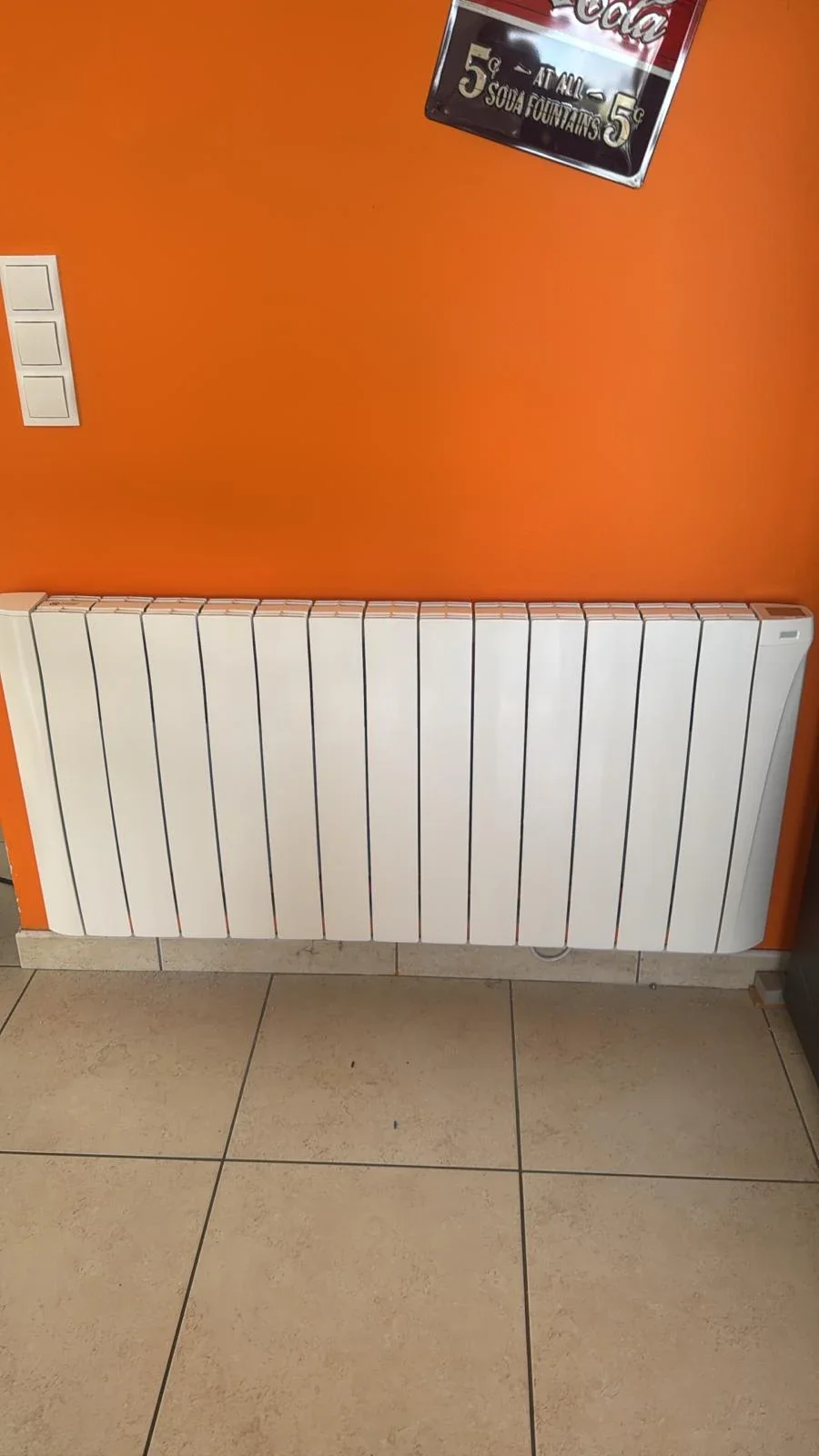 Radiateur Eco Chaleur installé sur mur orange dans une pièce de vie