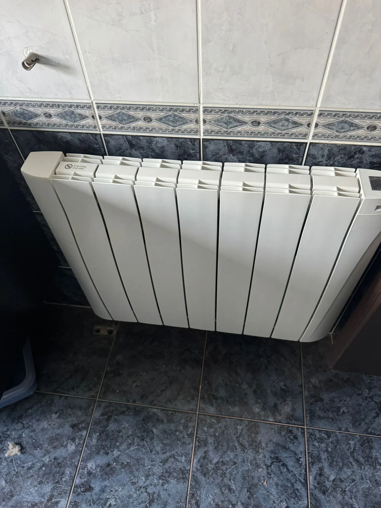 Radiateur Eco Chaleur installé dans une salle de bain sous un porte-serviettes