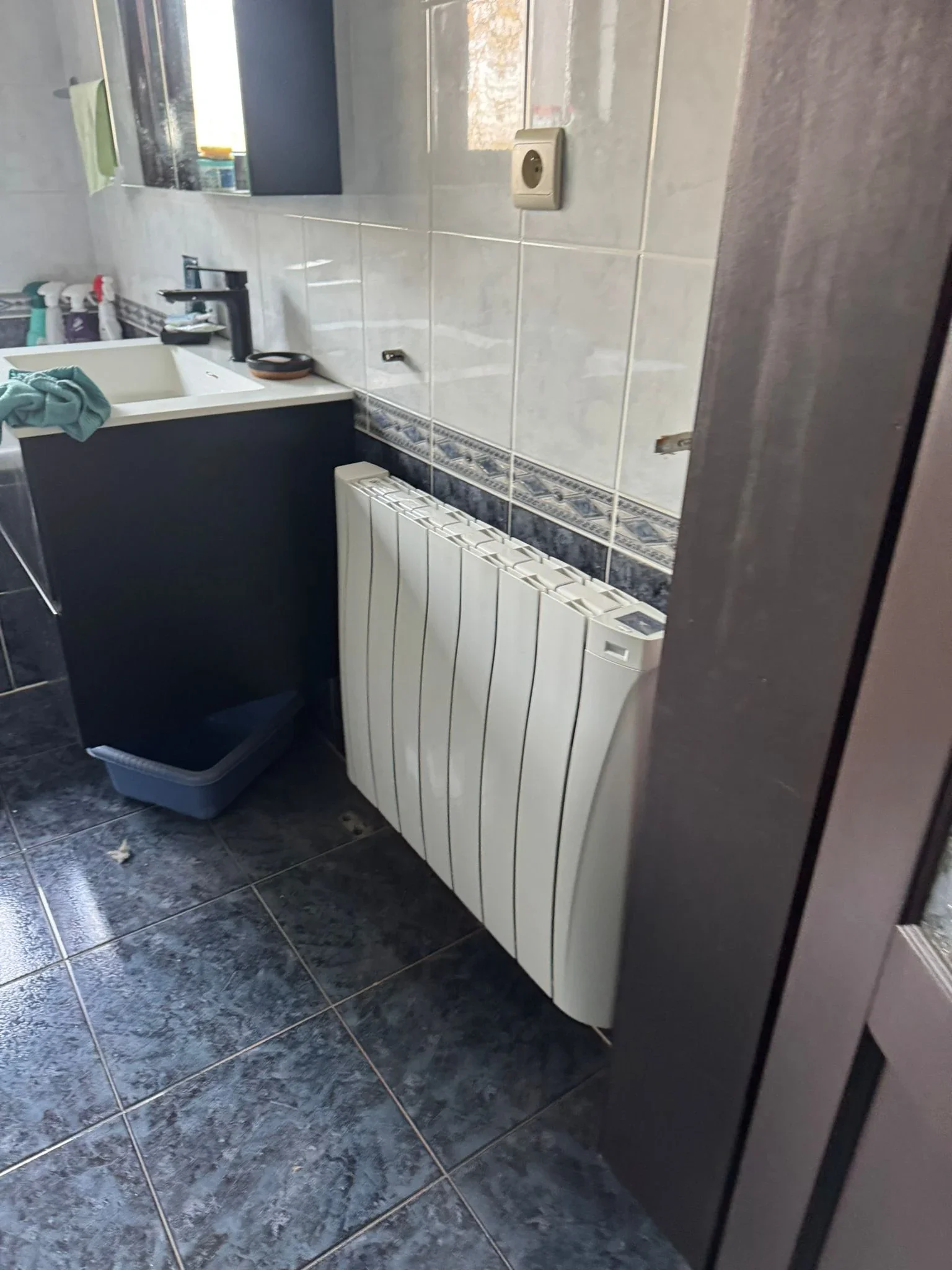 Radiateur Eco Chaleur installé dans une salle de bain à côté d'un meuble vasque