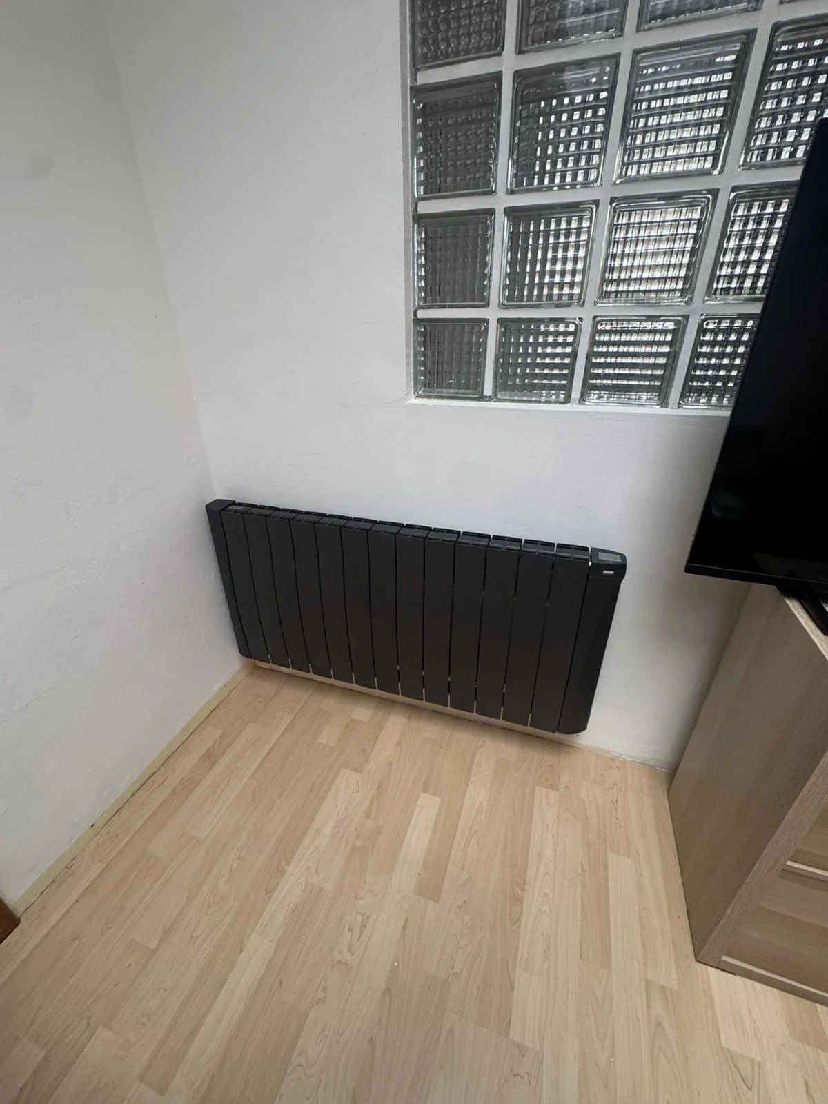 Radiateur anthracite Eco Chaleur sous fenêtre dans un coin télé