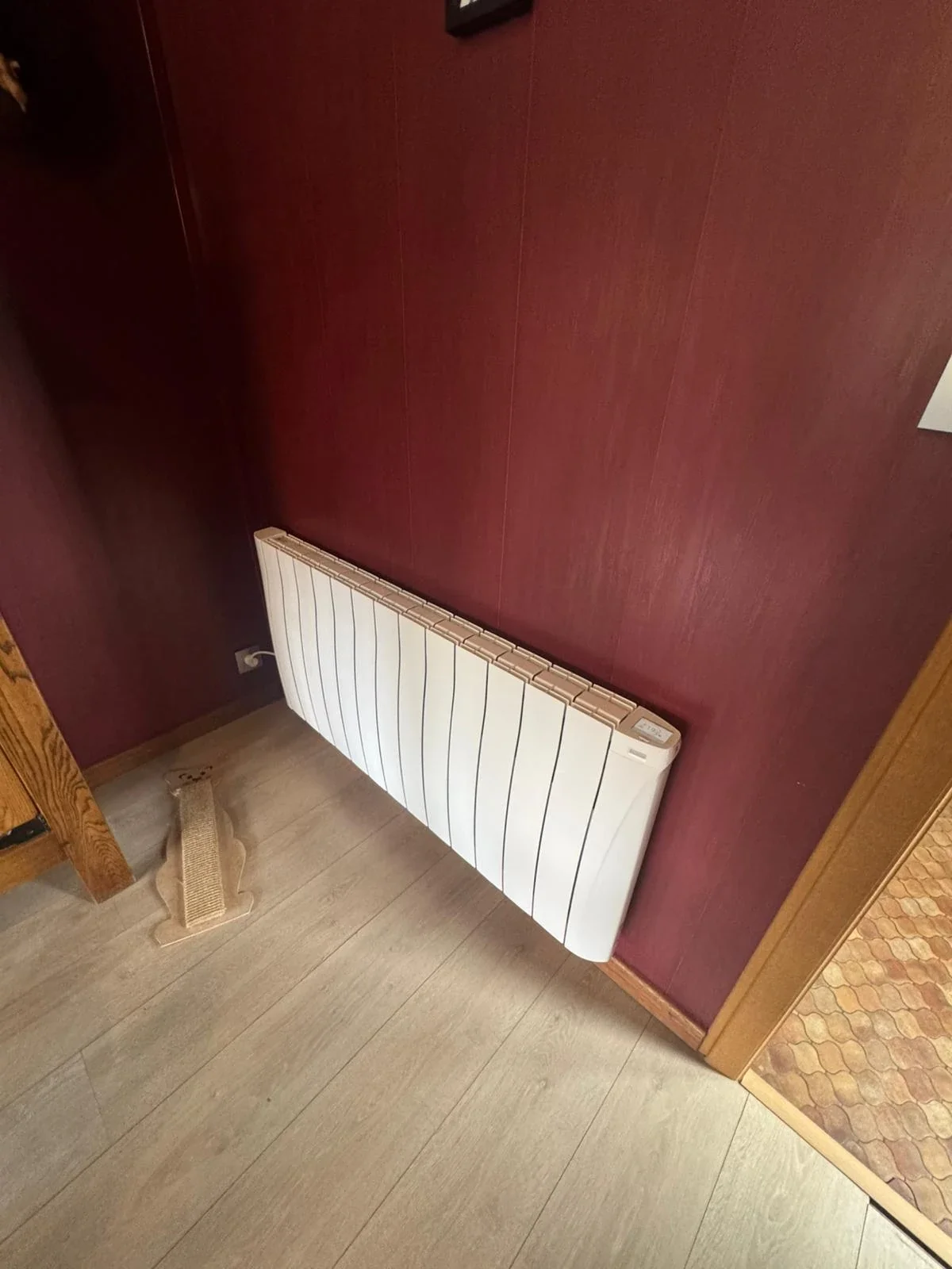Radiateur Eco Chaleur installé sur mur bordeaux dans une pièce de vie