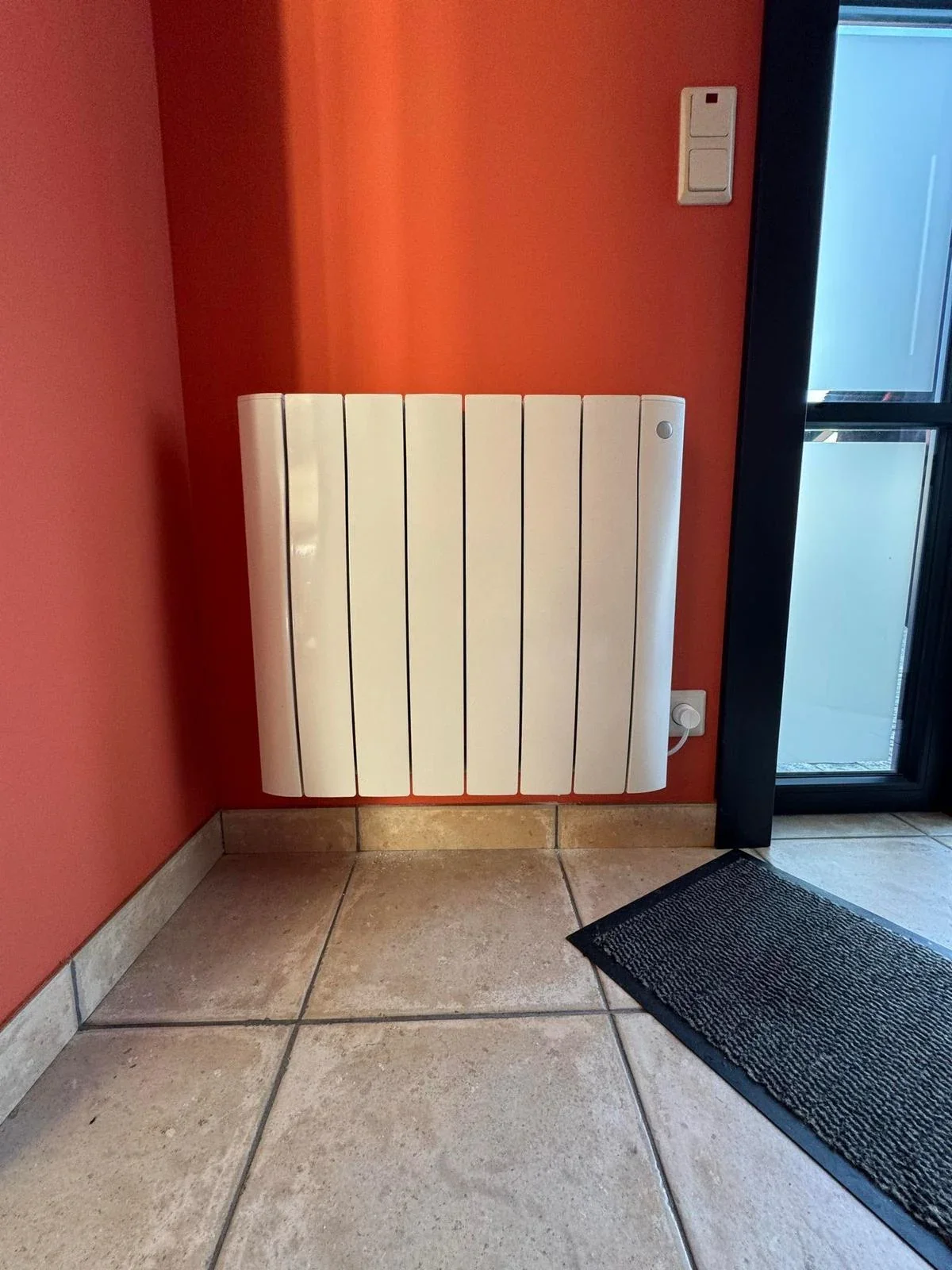 Radiateur Eco Chaleur installé sur mur rouge dans une entrée