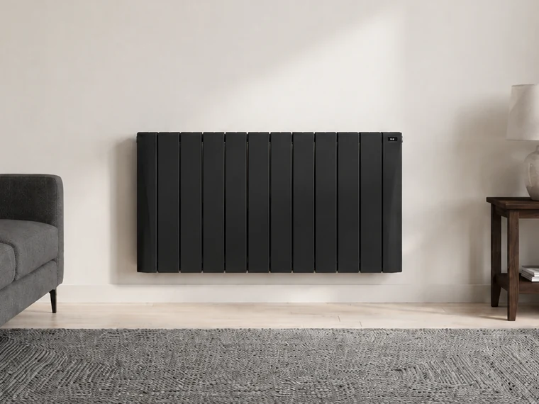 Radiateur Eco Chaleur en pierre stéatite anthracite installé sur un mur clair dans un salon contemporain belge